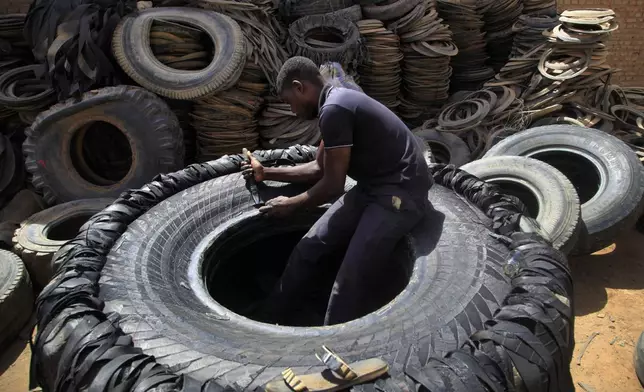 FILE - A Sudanese man cuts a heavy duty machine tire into rubber pieces at a shop in a market in Omdurman, Khartoum, Sudan, May 12, 2014. (AP Photo/Abd Raouf, File)