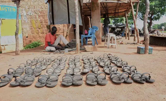 Shoemaker Emmanuel Achuil works under the shade of a tarpaulin in Wau, South Sudan, June 13, 2025. (AP Photo/Michael Atit)