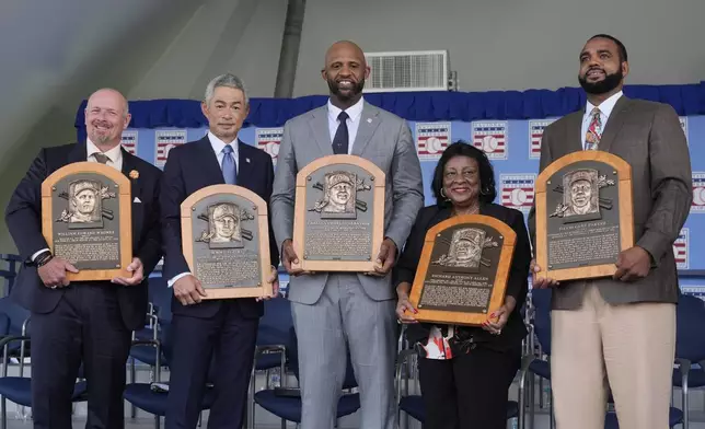 Baseball Hall of Fame inductees Billy Wagner, left, Ichiro Suzuki, second from left, and CC Sabathia, center, pose for a photo with Willa Allen, second from right, widow of Baseball Hall of Fame inductee Dick Allen, and Dave Parker II, right, son of the late Baseball Hall of Fame inductee Dave Parker, at the National Baseball Hall of Fame induction ceremony in Cooperstown, N.Y., Sunday, July 27, 2025. (AP Photo/Seth Wenig)