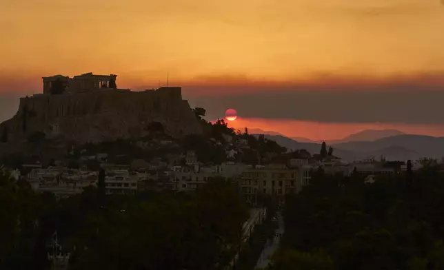The sun sets behind the Acropolis hill as smoke from a nearby wildfire fills the sky during a heatwave in Athens, Greece, Saturday, July 26, 2025. (AP Photo/Petros Giannakouris)