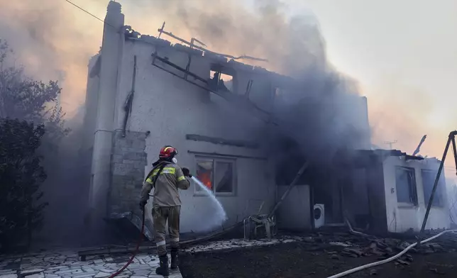 A firefighter tries to extinguish the blazes at a burning house during a wildfire, in the northwestern suburb of Kryoneri, in Athens, Greece, Saturday, July 26, 2025. (AP Photo/Yorgos Karahalis)