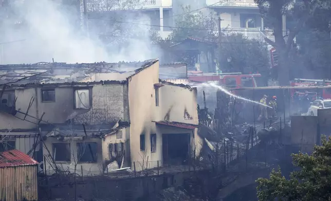 Firefighters try to extinguish a fire at a house during a wildfire, in the northwestern suburb of Kryoneri, in Athens, Greece, Saturday, July 26, 2025. (AP Photo/Yorgos Karahalis)