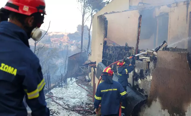 Firefighters try to extinguish a fire at house during a wildfire, in the northwestern suburb of Kryoneri, in Athens, Greece, Saturday, July 26, 2025. (AP Photo/Yorgos Karahalis)