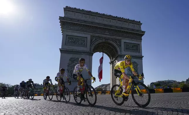 FILE - Slovenia's Tadej Pogacar, wearing the overall leader's yellow jersey, passes the Arc de Triomphe during the twenty-first and last stage of the Tour de France cycling race over 108.4 kilometers (67.4 miles) with start in Chatou and finish on the Champs Elysees in Paris, France,Sunday, July 18, 2021. (AP Photo/Daniel Cole, File)