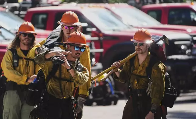 Wildland firefighters with the United States Forest Service prepare at a staging area near the scene the day after a shooter ambushed and killed multiple firefighters responding to a wildfire at Canfield Mountain Monday, June 30, 2025, in Coeur D'Alene, Idaho. (AP Photo/Lindsey Wasson)