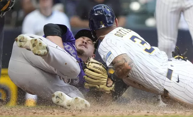 Milwaukee Brewers' Joey Ortiz (3) scores on a wild pitch past a tag by Colorado Rockies' Victor Vodnik, left, during the 10th inning of a baseball game Sunday, June 29, 2025, in Milwaukee. (AP Photo/Aaron Gash)
