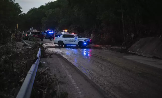Law enforcement officials block a road along the Guadalupe River as they load an extricated body into the back of a pickup truck in Hunt, Texas, Monday, July 7, 2025, after a flash flood swept through the area. (AP Photo/Eli Hartman)