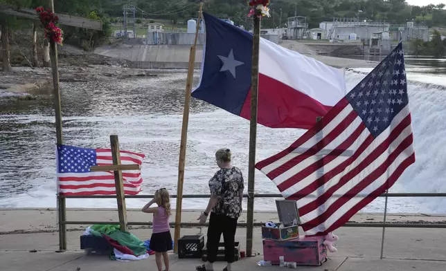 Nancy Epperson, right, and Brooklyn Pucek, 6, visit a memorial for flood victims along the Guadalupe River on Thursday, July 10, 2025, in Kerrville, Texas. (AP Photo/Gerald Herbert)