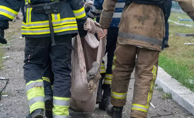 Rescuers carry a body of a civilian who was killed in Russia's missile attack that hit a residential building in Kharkiv, Ukraine, Monday, Aug. 18, 2025. (AP Photo/Andrii Marienko)