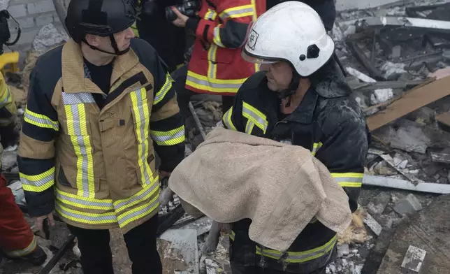 A rescuer carries a body of child from a residential building damaged by a Russia's missile attack on Kharkiv, Ukraine, Monday, Aug. 18, 2025. (AP Photo/Andrii Marienko)