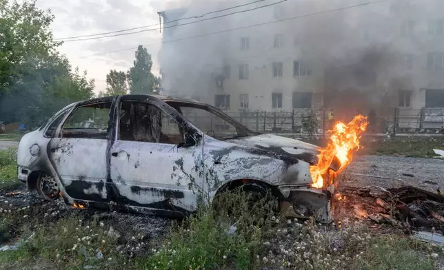 A car burns against the background of a damaged residential building following Russia's missile attack in Kharkiv, Ukraine, Monday, Aug. 18, 2025. (AP Photo/Andrii Marienko)