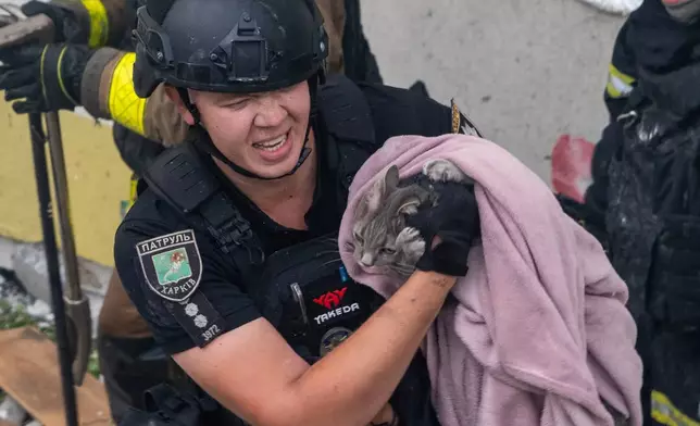 Firefighters evacuate a cat during search and rescue works in the damaged residential building following Russia's missile attack in Kharkiv, Ukraine, Monday, Aug. 18, 2025. (AP Photo/Andrii Marienko)