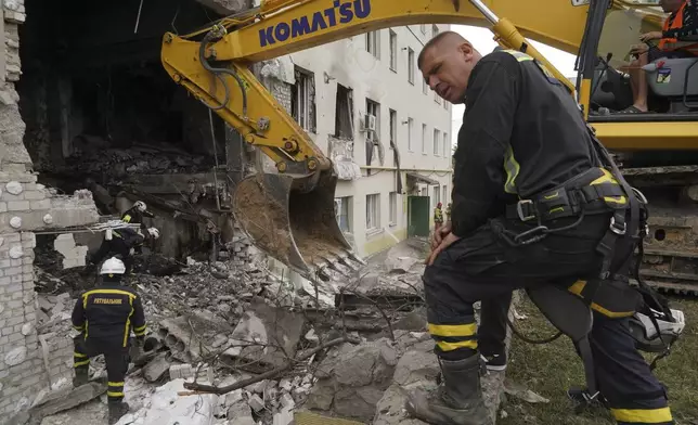 Rescue workers clear the rubble at a residential building damaged by a Russian attack on Kharkiv, Ukraine, Monday, Aug. 18, 2025. (AP Photo/Andrii Marienko)