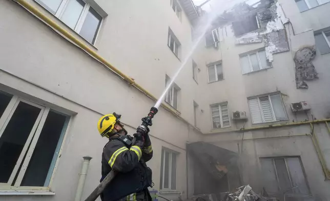 A firefighter puts out the fire in the damaged residential building following Russia's missile attack in Kharkiv, Ukraine, Monday, Aug. 18, 2025. (AP Photo/Andrii Marienko)
