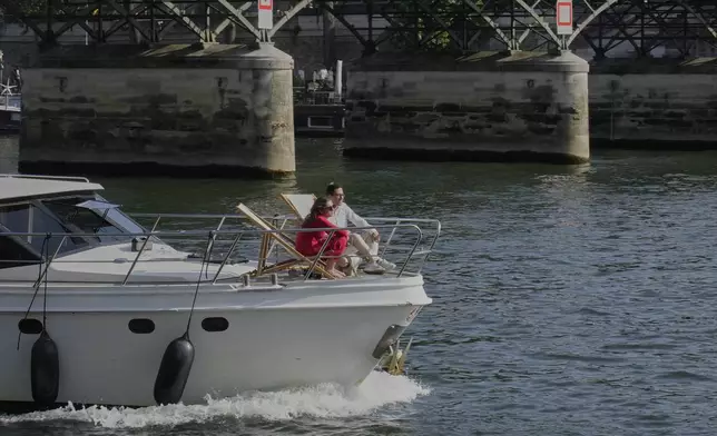 People enjoy the sun on a boat on the Seine river in Paris, Sunday, Aug. 10, 2025. (AP Photo/Michel Euler)