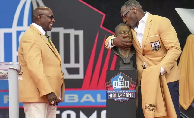 Former NFL player Sterling Sharpe, left, watches as his brother Shannon Sharpe kisses his bust during an induction ceremony at the Pro Football Hall of Fame, in Canton, Ohio, Saturday, Aug. 2, 2025, in Canton, Ohio. (AP Photo/Sue Ogrocki)