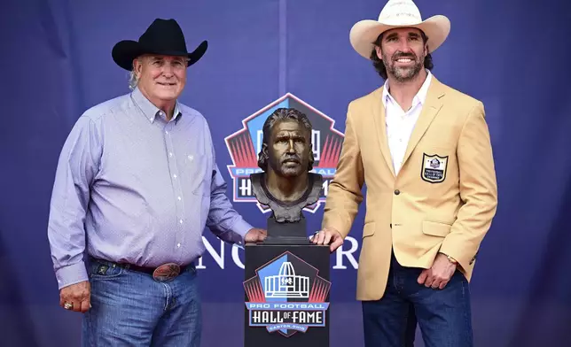 Former NFL player Jared Allen, right, accompanied by his father, Ronald Allen, pose with Jared's bust during an induction ceremony at the Pro Football Hall of Fame in Canton, Ohio, Saturday, Aug. 2, 2025. (AP Photo/David Dermer)