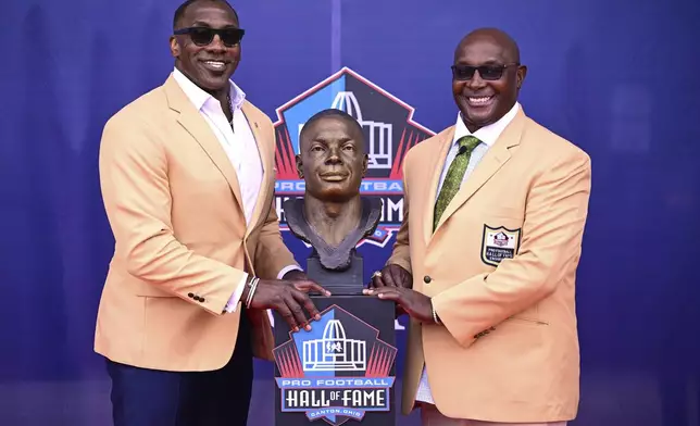 Former NFL player Sterling Sharpe, right, and his brother Shannon Sharpe pose with his bust during an induction ceremony at the Pro Football Hall of Fame, in Canton, Ohio, Saturday, Aug. 2, 2025, in Canton, Ohio. (AP Photo/David Dermer)