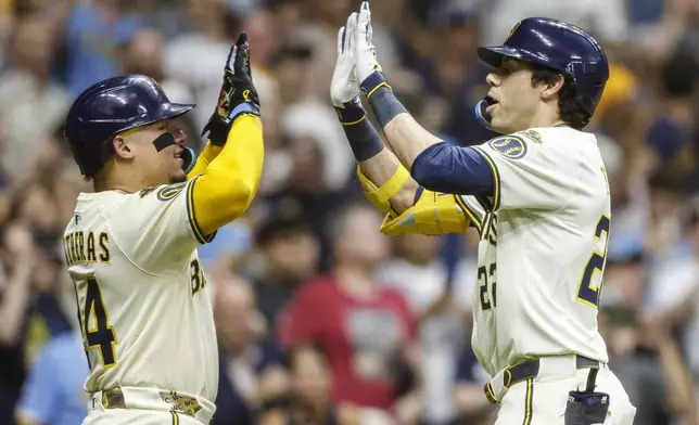 Milwaukee Brewers' Christian Yelich, right, high-fives with William Contreras after Yelich hit a two-run home run against the Pittsburgh Pirates during the fifth inning of a baseball game, Tuesday, Aug.12, 2025, in Milwaukee. (AP Photo/Jeffrey Phelps)