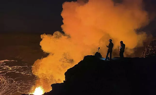 FILE - In this image provided the. the U.S. Geological Survey (USGS), geologist deployed to the rim look over evening views of lava fountaining from Haleumaumau Crater at the summit of Kilauea volcano inside Hawaii Volcanoes National Park, Hawaii., Feb. 11, 2025. ( J. Barnett/U.S. Geological Survey via AP, File)