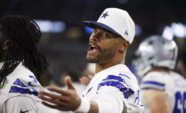 Dallas Cowboys quarterback Dak Prescott talks with teammates on the sideline in the second half of a preseason NFL football game against the Baltimore Ravens Saturday, Aug. 16, 2025, in Arlington, Texas. (AP Photo/Gareth Patterson)