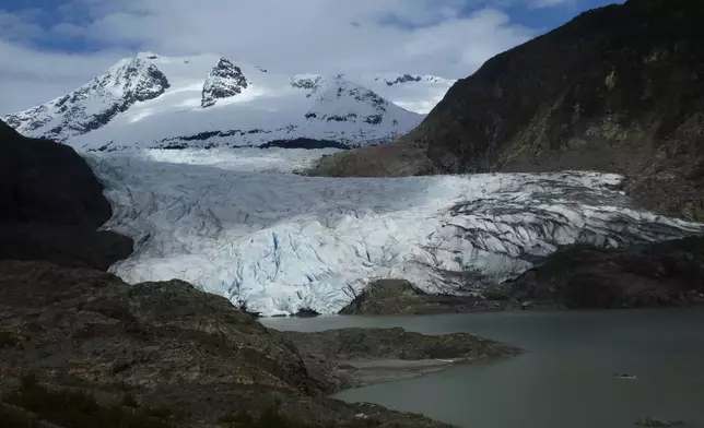 FILE - A canoe, bottom right, glides on Mendenhall Lake, in front of the Mendenhall Glacier, on Sunday, May 18, 2025, in Juneau, Alaska. (AP Photo/Becky Bohrer, File)