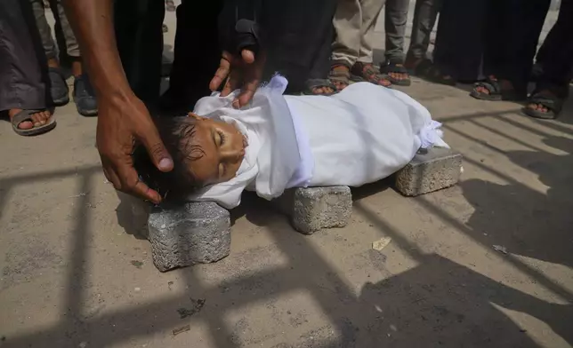 The body of 5-year-old Jamal al-Najjar is placed on the ground atop bricks before a funeral prayer after he died at Nasser Hospital in Khan Younis, southern Gaza Strip, Tuesday, Aug. 12, 2025. The head of Nasser's pediatrics unit said Jamal, who was born with rickets, died from severe malnutrition. (AP Photo/Mariam Dagga)