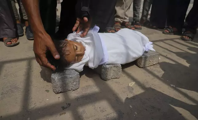 The body of 5-year-old Jamal al-Najjar is placed on the ground atop bricks before a funeral prayer after he died at Nasser Hospital in Khan Younis, southern Gaza Strip, Tuesday, Aug. 12, 2025. The head of Nasser's pediatrics unit said Jamal, who was born with rickets, died from severe malnutrition. (AP Photo/Mariam Dagga)