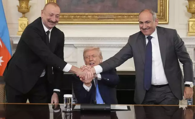 President Donald Trump, center, shakes hands with Armenian Prime Minister Nikol Pashinyan, right, and Azerbaijan President Ilham Aliyev during a trilateral signing ceremony in the State Dining Room of the White House, Friday, Aug. 8, 2025, in Washington. (AP Photo/Mark Schiefelbein)