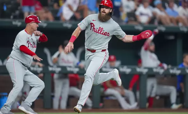 Philadelphia Phillies' Brandon Marsh runs home while scoring on a two-run double by teammate Max Kepler during the seventh inning of a baseball game against the Texas Rangers Saturday, Aug. 9, 2025, in Arlington, Texas. (AP Photo/Julio Cortez)
