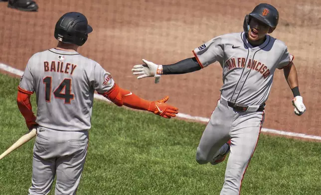 San Francisco Giants' Jung Hoo Lee, right, is greeted by Patrick Bailey (14) after scoring on a double by Dominic Smith off Pittsburgh Pirates pitcher Dennis Santana during the ninth inning of a baseball game in Pittsburgh, Wednesday, Aug. 6, 2025. (AP Photo/Gene J. Puskar)