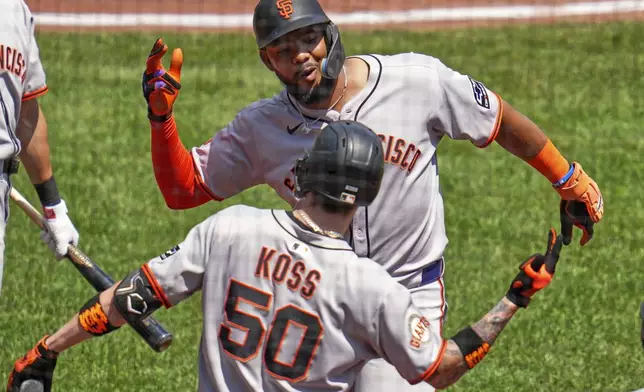 San Francisco Giants' Jerar Encarnacion, top, celebrates with Christian Koss (50) as he returns to the dugout after hitting a solo home run off Pittsburgh Pirates pitcher Andrew Heaney during the fifth inning of a baseball game in Pittsburgh, Wednesday, Aug. 6, 2025. (AP Photo/Gene J. Puskar)