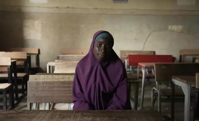 Ramatu Usman, who was dropped by the school of Future Prowess Islamic Foundation poses for a photo at a desk inside her former class, in Maiduguri, Nigeria, Thursday, July 24, 2025. (AP Photo/Sunday Alamba)