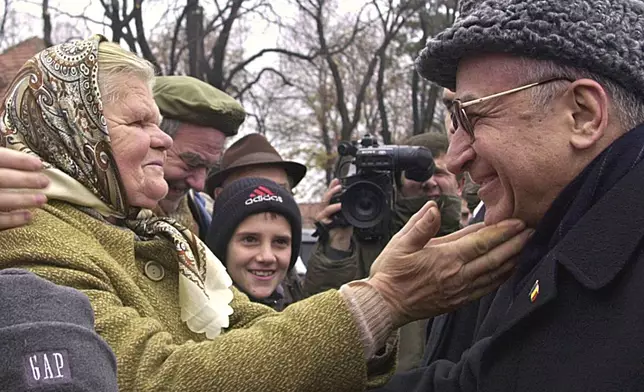 FILE - An elderly Romanian woman reaches out to President Ion Iliescu, right, at the end of celebrations for Romania's national day in Bucharest on Saturday, Dec. 1 2001. (AP Photo/Vadim Ghirda, File)