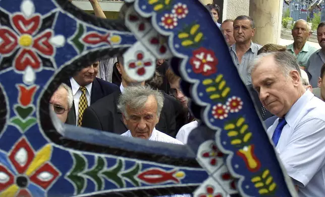 FILE - Nobel peace laureate Elie Wiesel, left, looks at a traditional Romanian cross together with Romanian President Ion Iliescu in the Sapanta cemetrey, northern Romania, Monday July 29, 2002. (AP Photo/File)