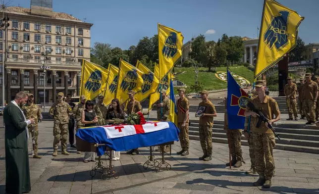 Soldiers of the Azov Regiment pay last respect at the coffin of their comrade, Georgian volunteer Mykhailo Kovaliv, during a farewell ceremony on Independence Square in Kyiv, Ukraine, Saturday, Aug. 9, 2025. (AP Photo/Dan Bashakov)