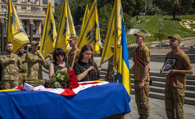Relatives and soldiers of the Azov Regiment pay last respect near the coffin of their comrade, Georgian volunteer Mykhailo Kovaliv, during a farewell ceremony on Independence Square in Kyiv, Ukraine, Saturday, Aug. 9, 2025. (AP Photo/Dan Bashakov)