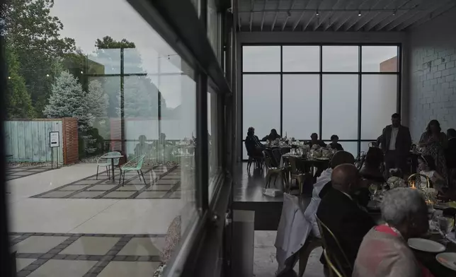 Guests sit inside during cocktail hour as empty chairs sit outside during a wedding Saturday, Aug. 23, 2025, in Newtown, Ohio. (AP Photo/Joshua A. Bickel)