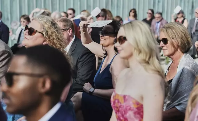 A guest uses a fan to shade from the sun during a wedding ceremony Saturday, Aug. 23, 2025, in Newtown, Ohio. (AP Photo/Joshua A. Bickel)
