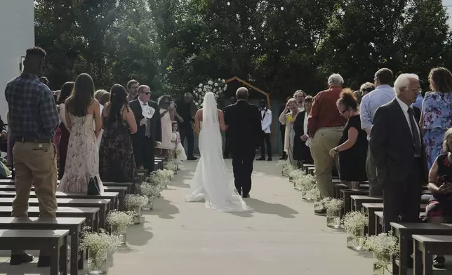 Kayla McDonald walks down the aisle with her father, Chris, during her wedding Saturday, Aug. 23, 2025, in Newtown, Ohio. (AP Photo/Joshua A. Bickel)