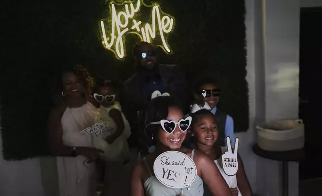 Bridesmaid Dakota-Jade Jones, front center, poses in a photo booth during a wedding reception Saturday, Aug. 23, 2025, in Newtown, Ohio. (AP Photo/Joshua A. Bickel)