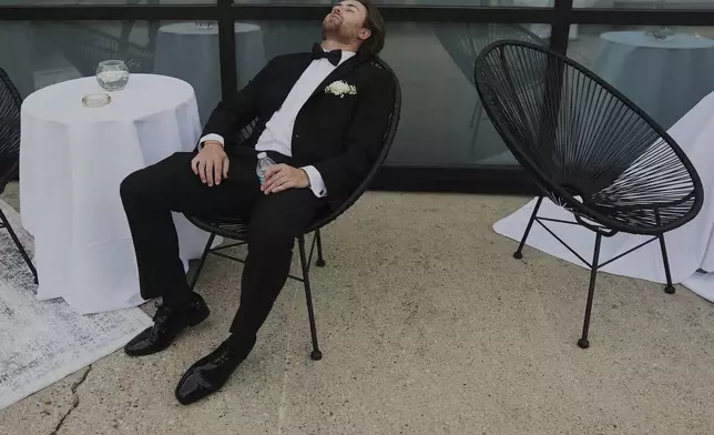 Groomsman Ethan Morton takes a break after finishing bridal party photos at a wedding on Saturday, Aug. 23, 2025, in Newtown, Ohio. (AP Photo/Joshua A. Bickel)