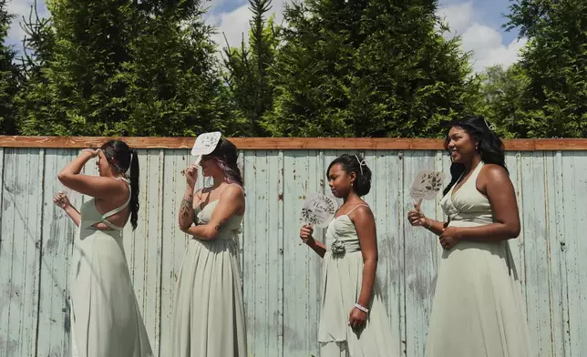Bridesmaids Alyssa Gunning, from left, Eve Shepherd, Dakota-Jade Jones and Ndiah Jones use fans for shade and to keep cool during bridal pictures before a wedding Saturday, Aug. 23, 2025, in Newtown, Ohio. (AP Photo/Joshua A. Bickel)