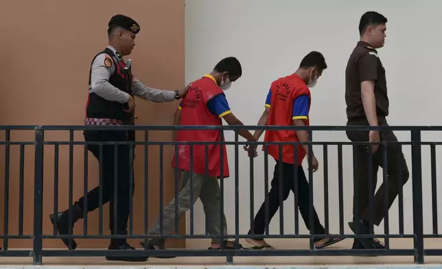A police officer and a prosecutor escort two men accused of having gay sex, upon arrival for their sentencing hearing at the Sharia Court in Banda Aceh, Indonesia, Monday, Aug. 11, 2025. (AP Photo/Reza Saifullah)