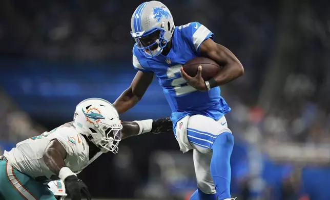 Detroit Lions quarterback Hendon Hooker (2) carries against Miami Dolphins linebacker Dequan Jackson during the second half of an NFL preseason football game Saturday, Aug. 16, 2025, in Detroit. (AP Photo/Ryan Sun)