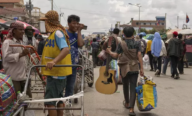 With a guitar in hand, a Cambodian migrant worker carries his belongings in Kamrieng, after crossing the Daung International Border Check Point between Cambodia and Thailand on Wednesday, Aug. 6, 2025. (AP Photo/Anton L. Delgado)