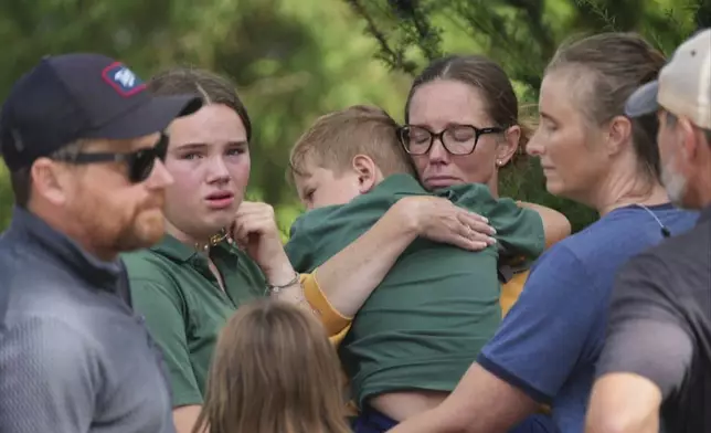 Parents comfort their children after a shooting at Annunciation Church on Wednesday, Aug. 27, 2025 in Minneapolis. (Alex Kormann/Star Tribune via AP)/