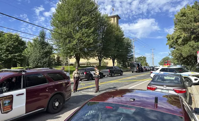 Law enforcement officers gather outside the Annunciation Church's school in response to a reported mass shooting, Wednesday, Aug. 27, 2025, in Minneapolis. (AP Photo/Mark Vancleave)