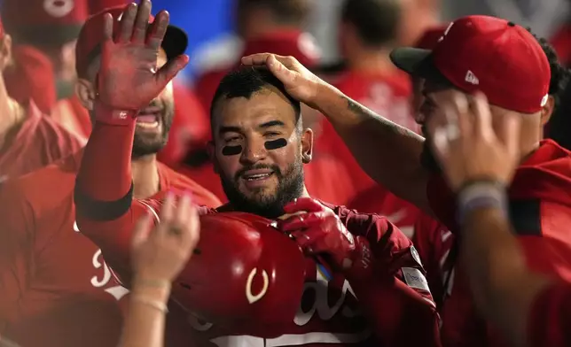 Cincinnati Reds' Jose Trevino is congratulated by teammates in the dugout after scoring on sacrifice by TJ Friedl during the ninth inning of a baseball game against the Los Angeles Angels, Tuesday, Aug. 19, 2025, in Anaheim, Calif. (AP Photo/Mark J. Terrill)