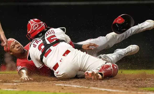 Cincinnati Reds' Will Benson, left, is tagged out by Los Angeles Angels catcher Travis d'Arnaud while trying to score on a double by Gavin Lux during the ninth inning of a baseball game Tuesday, Aug. 19, 2025, in Anaheim, Calif. (AP Photo/Mark J. Terrill)